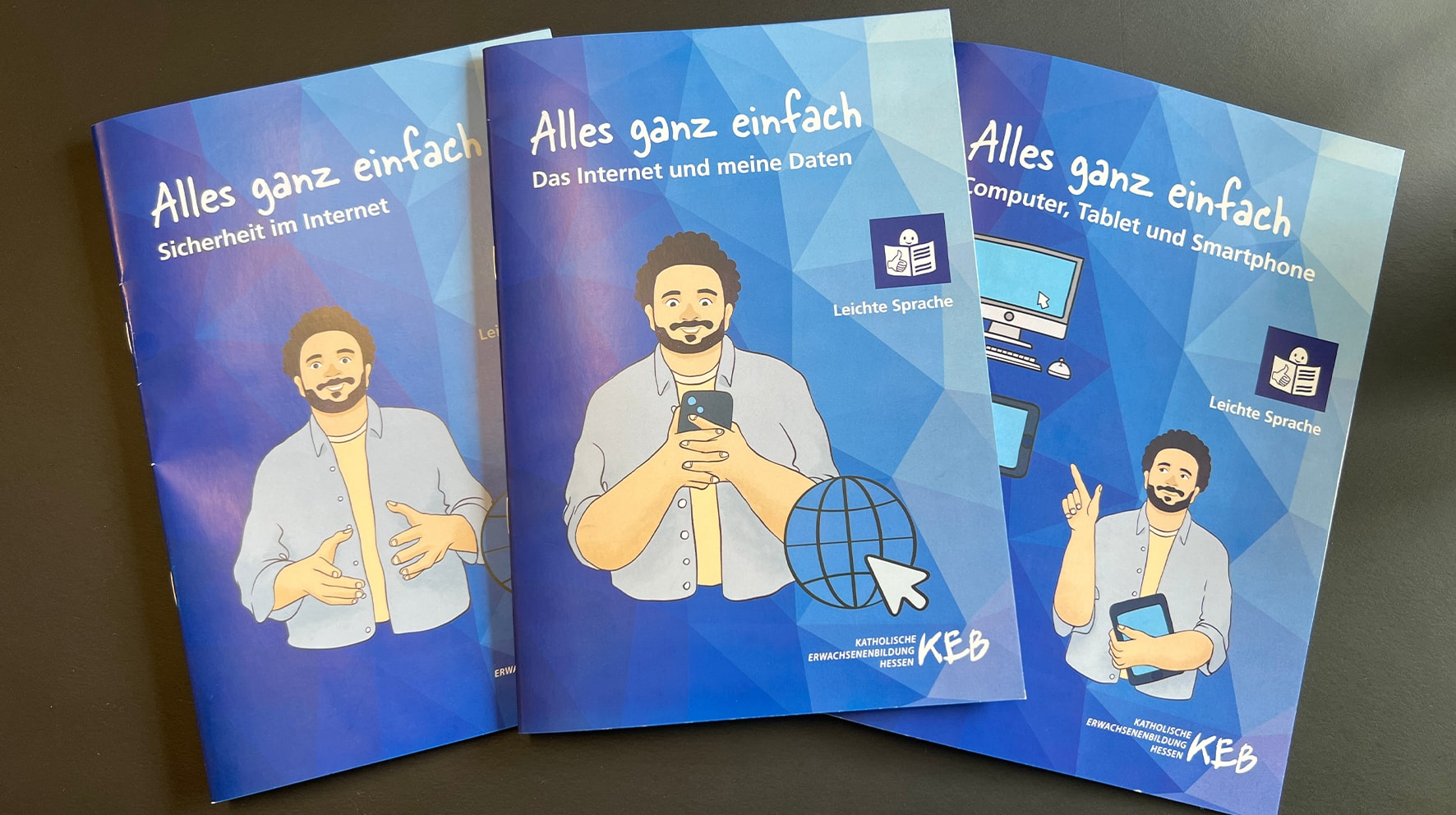 Das Bild zeigt drei Broschüren der Reihe „Alles ganz einfach“ mit den Themen "Sicherheit im Internet", "Das Internet und meine Daten" und "Computer, Tablet und Smartphone", die alle in leichter Sprache verfasst sind. Jede Broschüre hat ein blaues Cover und zeigt eine Illustration eines Mannes mit Bart und lockigen Haaren, der freundlich verschiedene Gesten macht. Die Broschüren stammen von der Katholischen Erwachsenenbildung Hessen (KEB).