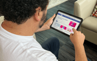 Eine Person sitzt auf einem Sessel und hält ein Tablet in der Hand. Auf dem Bildschirm ist die Startseite der Webseite Medien leicht erklärt mit verschiedenen Themenfeldern zu sehen.